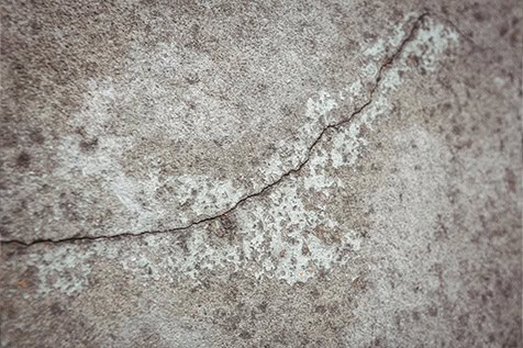 Close-up view of a cracked concrete surface with visible texture and discoloration.